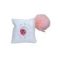 Personalized white decorative baby pillow featuring a baby photo inside a pink flower design and a fluffy pink pom-pom accent.