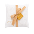 White textured fabric pouch decorated with a beige ribbon tied in a large bow, a small tan tag with gold lettering, and subtle gold details near the bottom.
