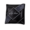 Black decorative pillow with silver geometric lines, textured accents, and white Hebrew lettering inside a central diamond design.