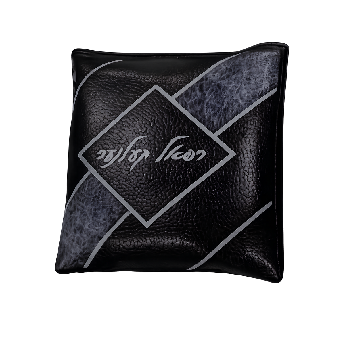 Black decorative pillow with silver geometric lines, textured accents, and white Hebrew lettering inside a central diamond design.