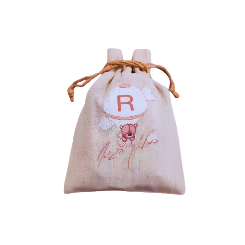 Personalized beige drawstring gift pouch featuring a teddy bear illustration, floral details, and a red monogram letter.
