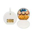 White round gift container with a gold personalized label, opened to reveal assorted colorful decorated cookies or treats arranged inside.