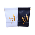 Set of two personalized favor pouches, one white and one black, featuring matching gold Hebrew letter designs.