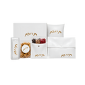 Personalized white gift set featuring matching pouches, envelopes, a decorative pillow, a small round container, and assorted treats with gold Hebrew lettering.