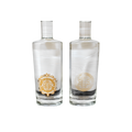 Pair of clear glass bottles with white caps, featuring elegant gold decorative designs and personalized labels.